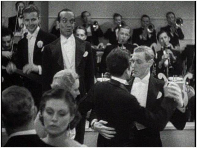 That's Dick Powell and Al Jolson smiling at the dancing male couple in the 1934 movie "Wonder Bar"